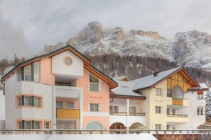 A multi-story hotel with balconies and a mountainous backdrop.