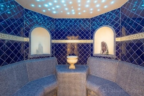 A room with a patterned blue and white tiled wall, a central decorative urn, and two sofas. - Ciasa LaRô (San Cassiano)