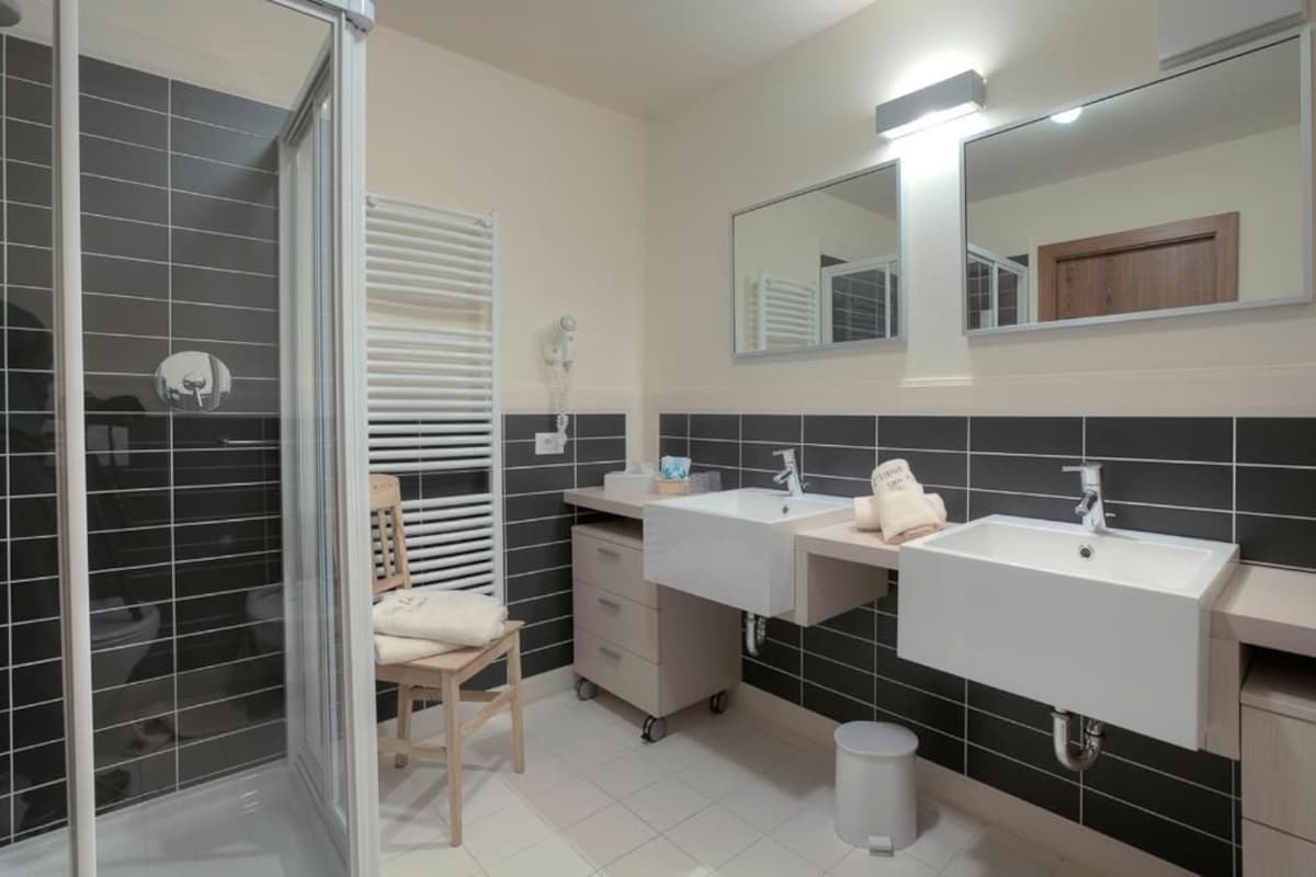 A bathroom with two sinks, a mirror, a towel rack, and a shower area.