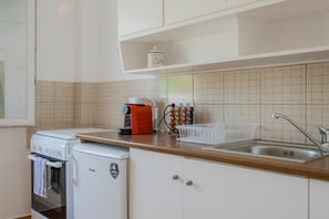 Una cocina compacta con cafetera, refrigerador pequeño y lavamanos.