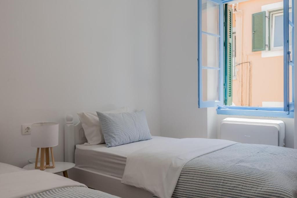Quarto com cama, mesa de cabeceira, abajur e janela com persianas.