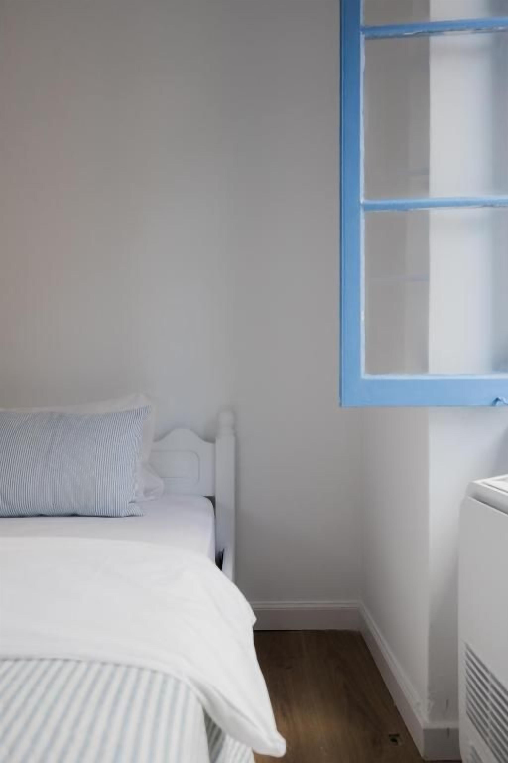 A bedroom with a bed, a radiator, and a window with blue trim.