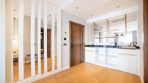 Una cocina moderna con armarios blancos, una encimera negra y una puerta de madera.