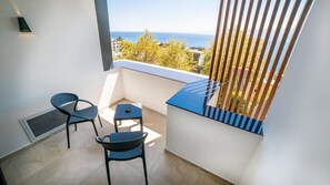 Un balcón con dos sillas, una mesita y vistas al mar.