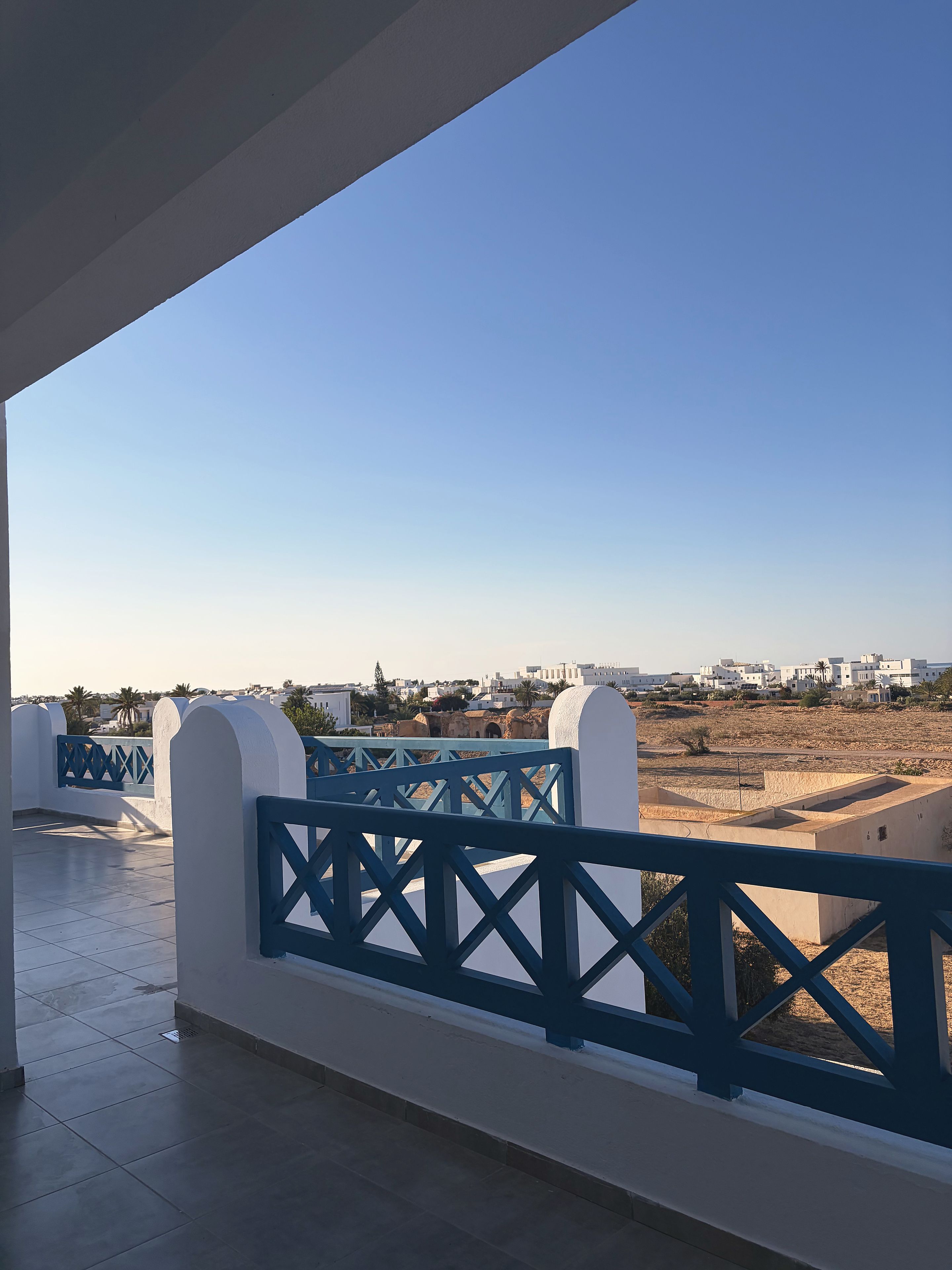 Un balcón con vistas a una zona residencial y un cielo despejado.