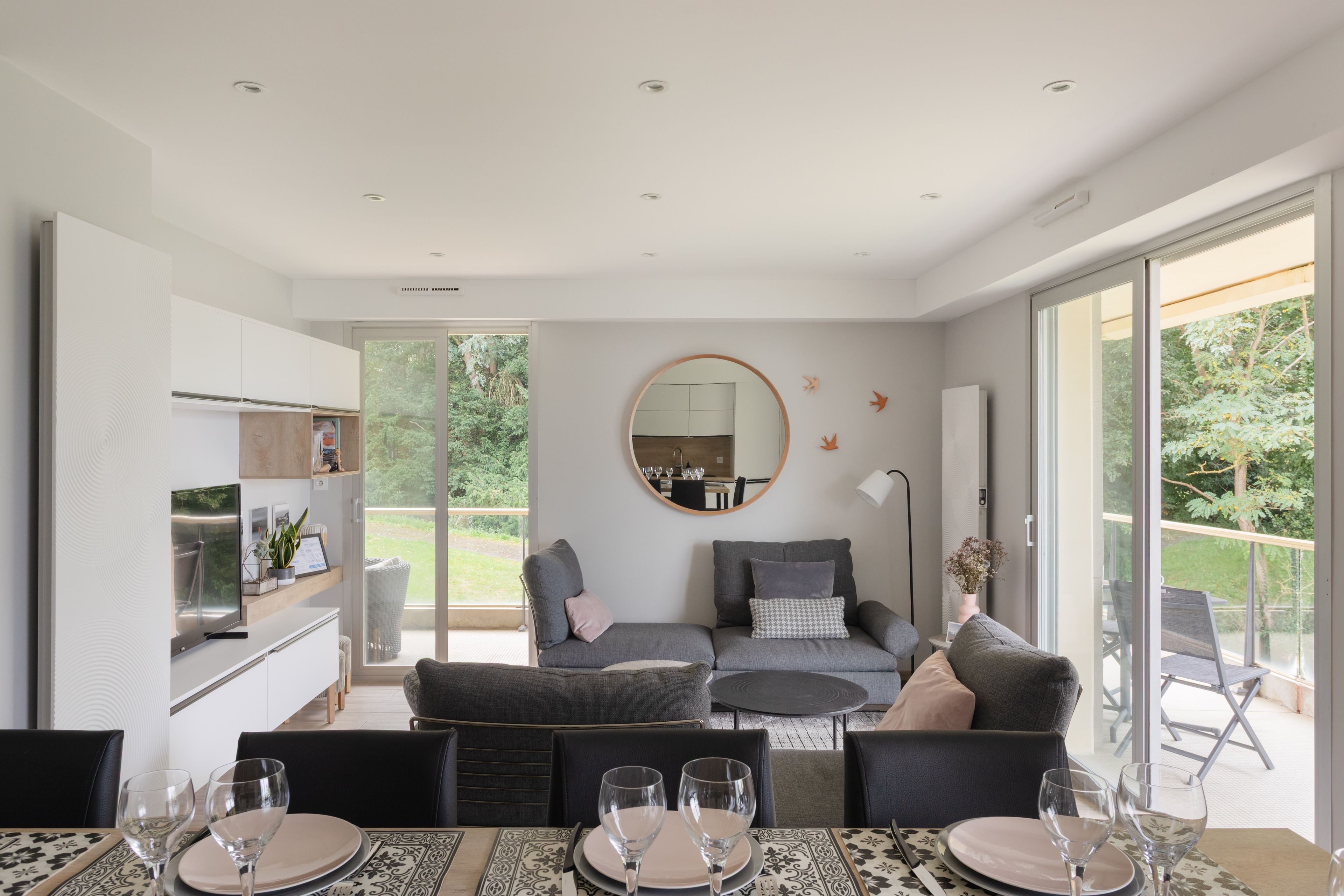 Un intérieur moderne comprenant un coin repas, un ensemble de canapés et une cuisine.