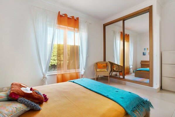 Een slaapkamer met een bed, een stoel, een grote spiegel en uitzicht op het landschap.