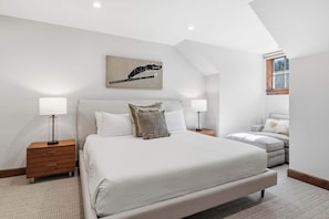A bedroom with a bed, two bedside tables, a lamp, a chair, and a window. - Ascent 401 - 3 Bedroom Residence (Avon)