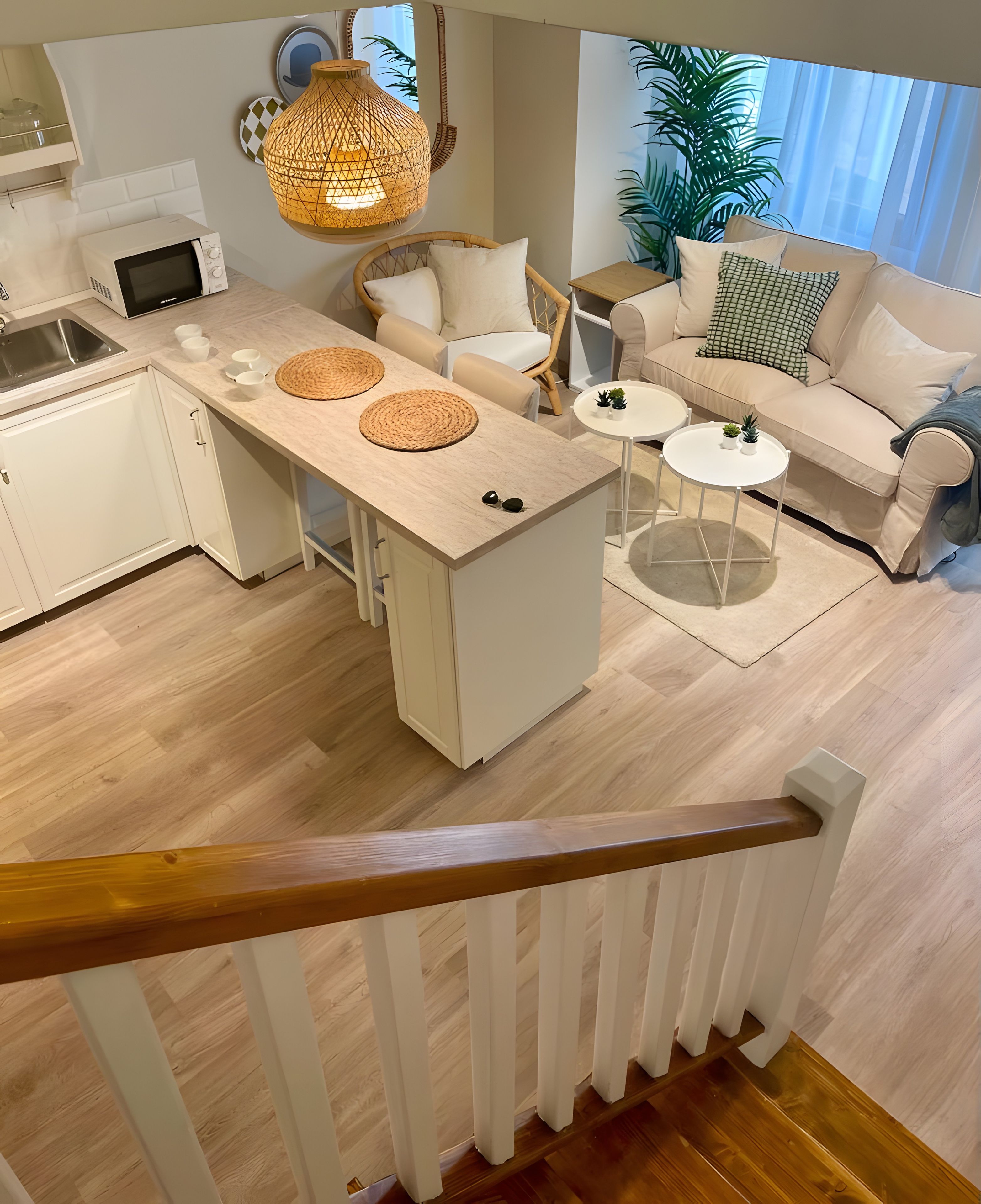 Una cocina moderna con una isla central, armarios blancos y una escalera de madera.