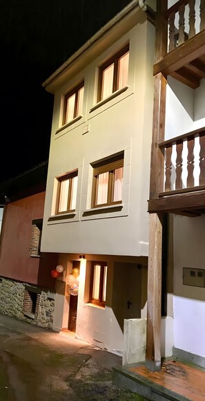 Ein zweistöckiges Gebäude mit Balkon, Steinmauer und einer Tür mit Leuchte.