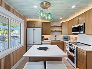 Une cuisine moderne dotée d’un îlot central, de meubles en bois, d’un four encastré et d’un four à micro-ondes.