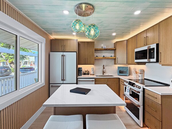 Una cocina moderna con una isla central, armarios de madera, horno empotrado y microondas.