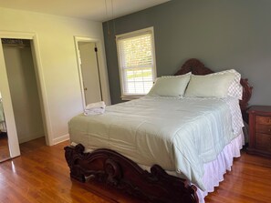 Une chambre à coucher avec un lit en bois, une fenêtre avec des stores et une porte donnant sur une autre pièce.