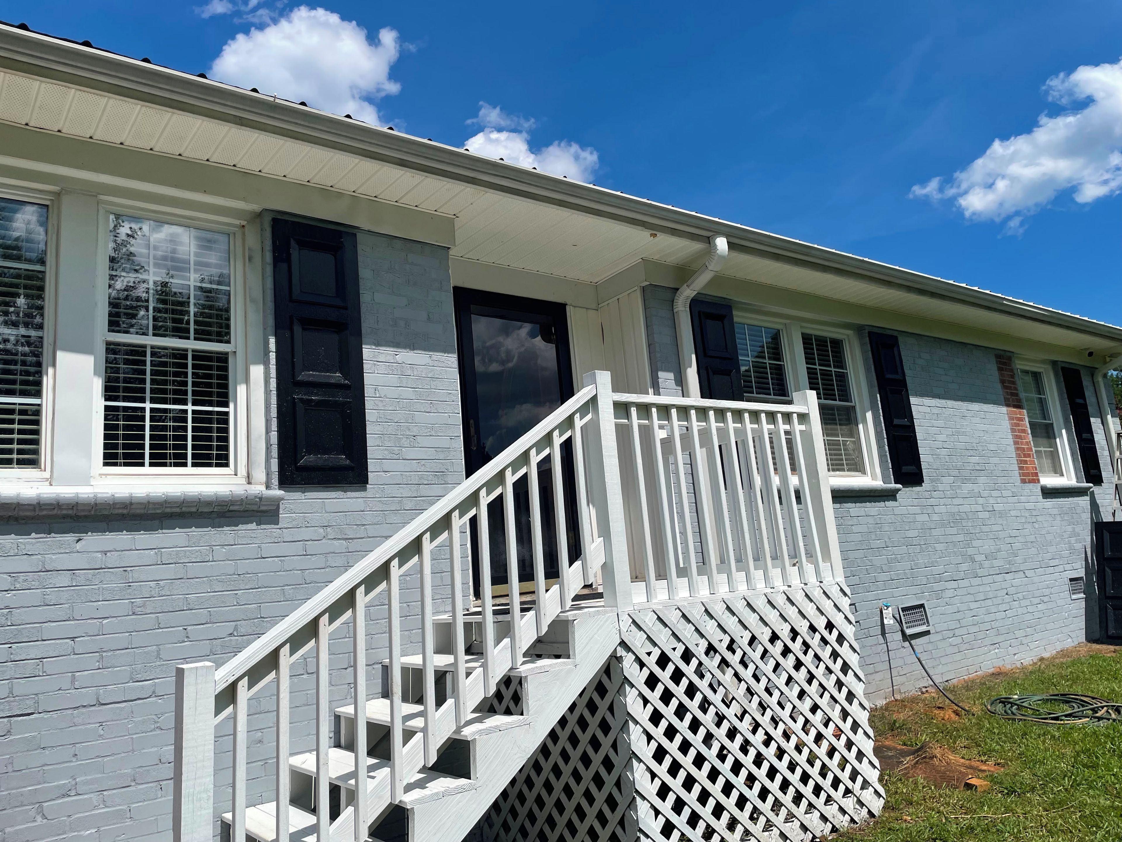 A two-story building with a white exterior, a front porch with a white railing, and a visible staircase leading to the second floor.