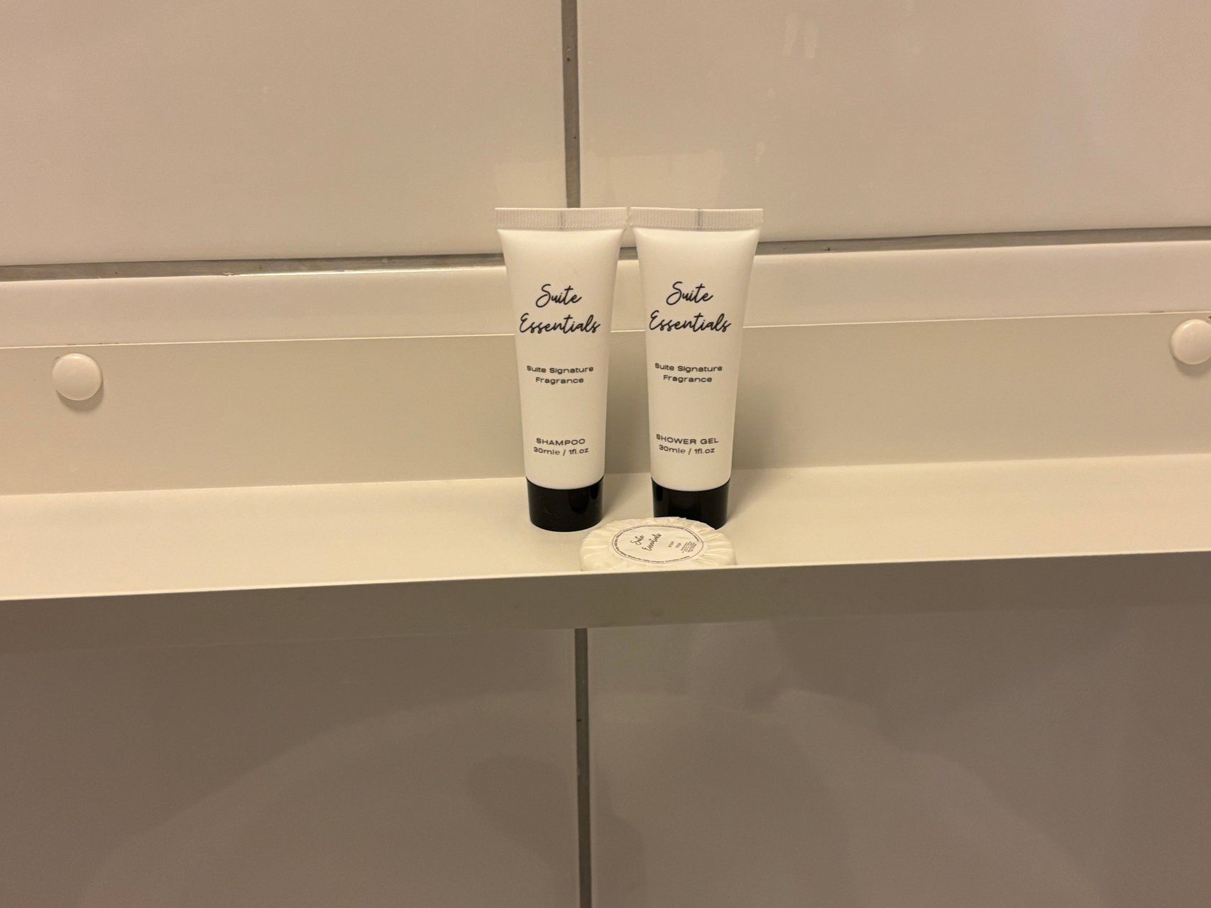 Two toiletry items on a white shelf in a bathroom.