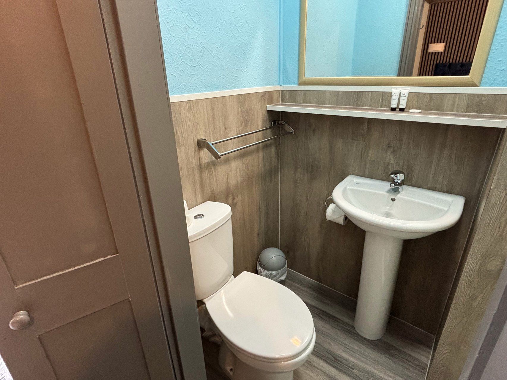 Een badkamer met toilet, wastafel en handdoekhouder.