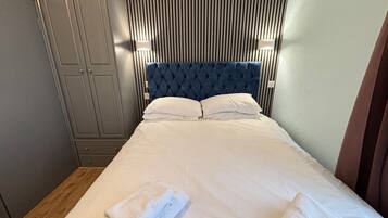 Una habitación de hotel con cama, armario y cabecera con líneas verticales.