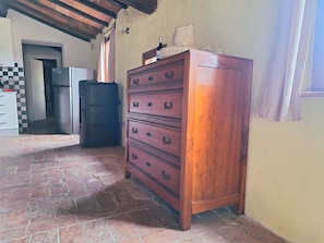 A wooden dresser with drawers, a tiled floor, a refrigerator, and a window with curtains. - Senti il Silenzio - sfeervol vakantiehuis in het authentieke Toscane (Caldana)