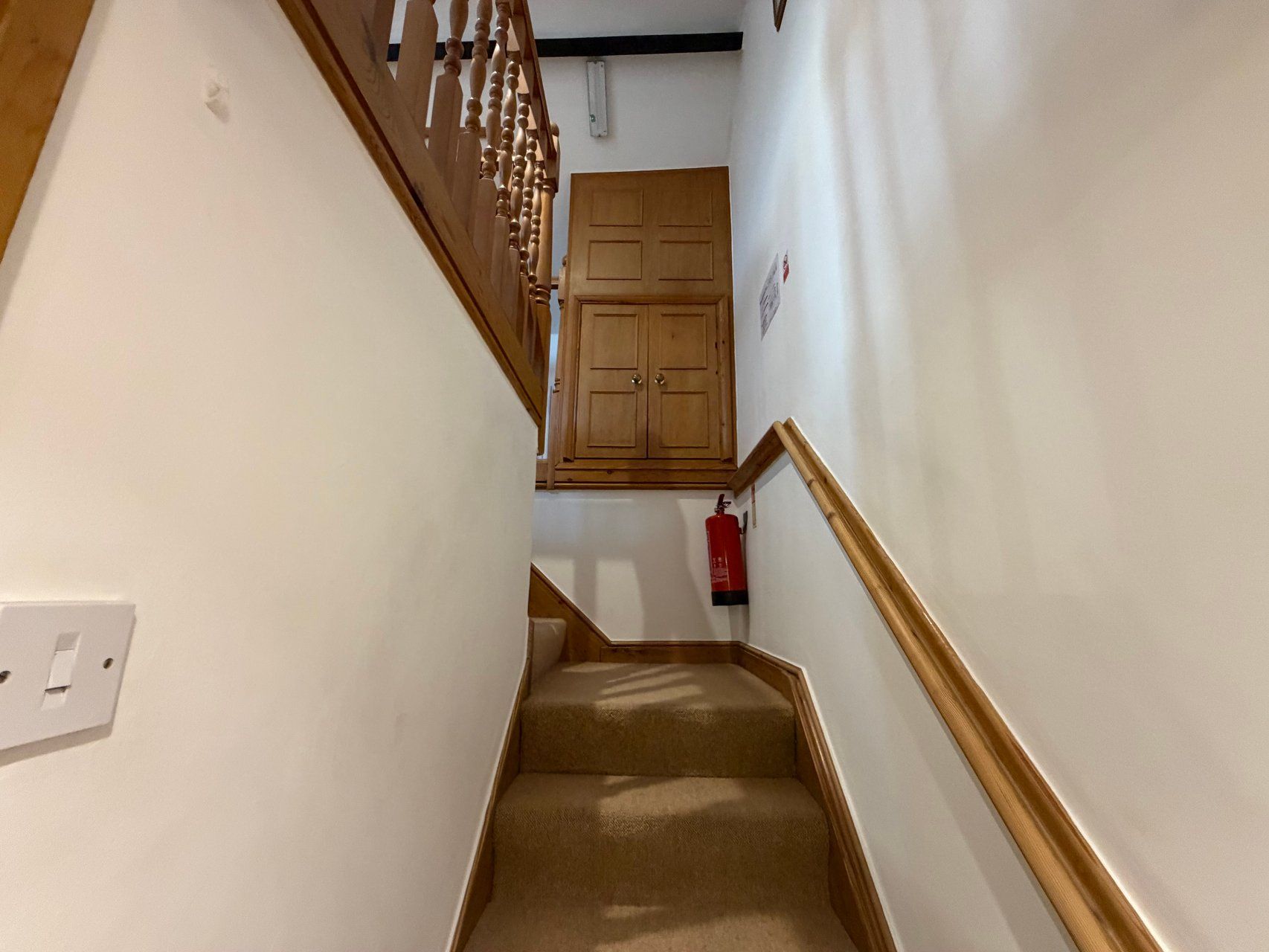 Una escalera estrecha con peldaños alfombrados que conduce a una puerta de madera.