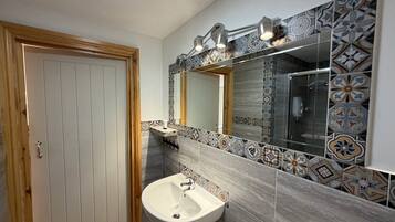 Un baño con puerta de madera, un lavamanos, un espejo y baldosas con diseño.