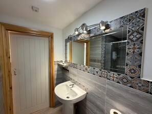 Un baño con puerta de madera, un lavamanos, un espejo y baldosas con diseño.