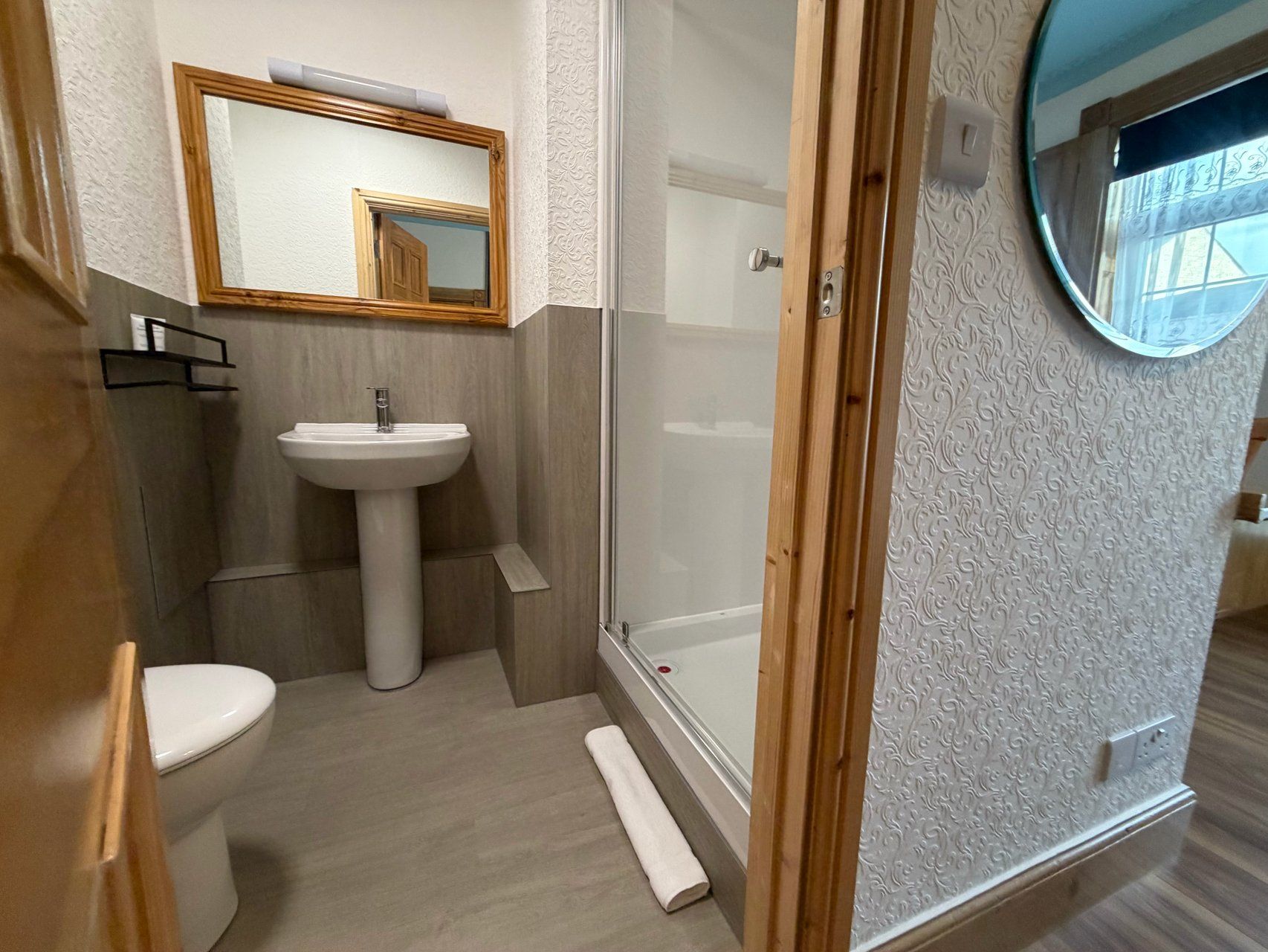 Un baño con lavamanos pedestal, inodoro, cabina de ducha y espejo.