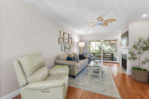 A living room with a sofa, armchair, and a ceiling fan.