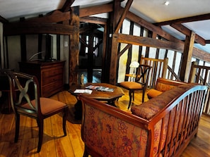 Una habitación con vigas de madera, una mesa de madera con revistas, un sofá y una silla.
