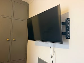 Et fladskærms-tv monteret på væggen med et tilsluttet kabel.