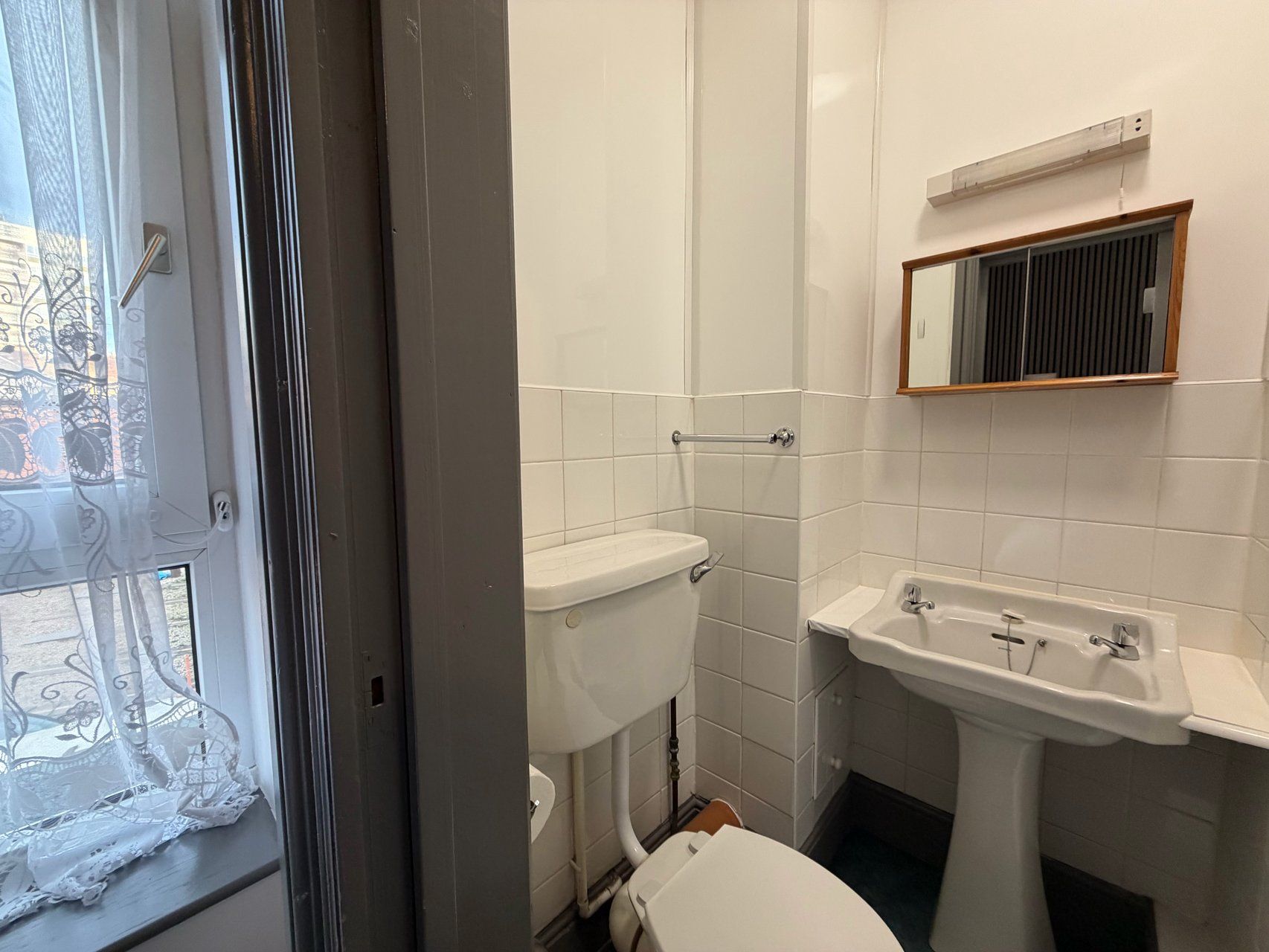 A bathroom with a toilet, sink, and mirror.
