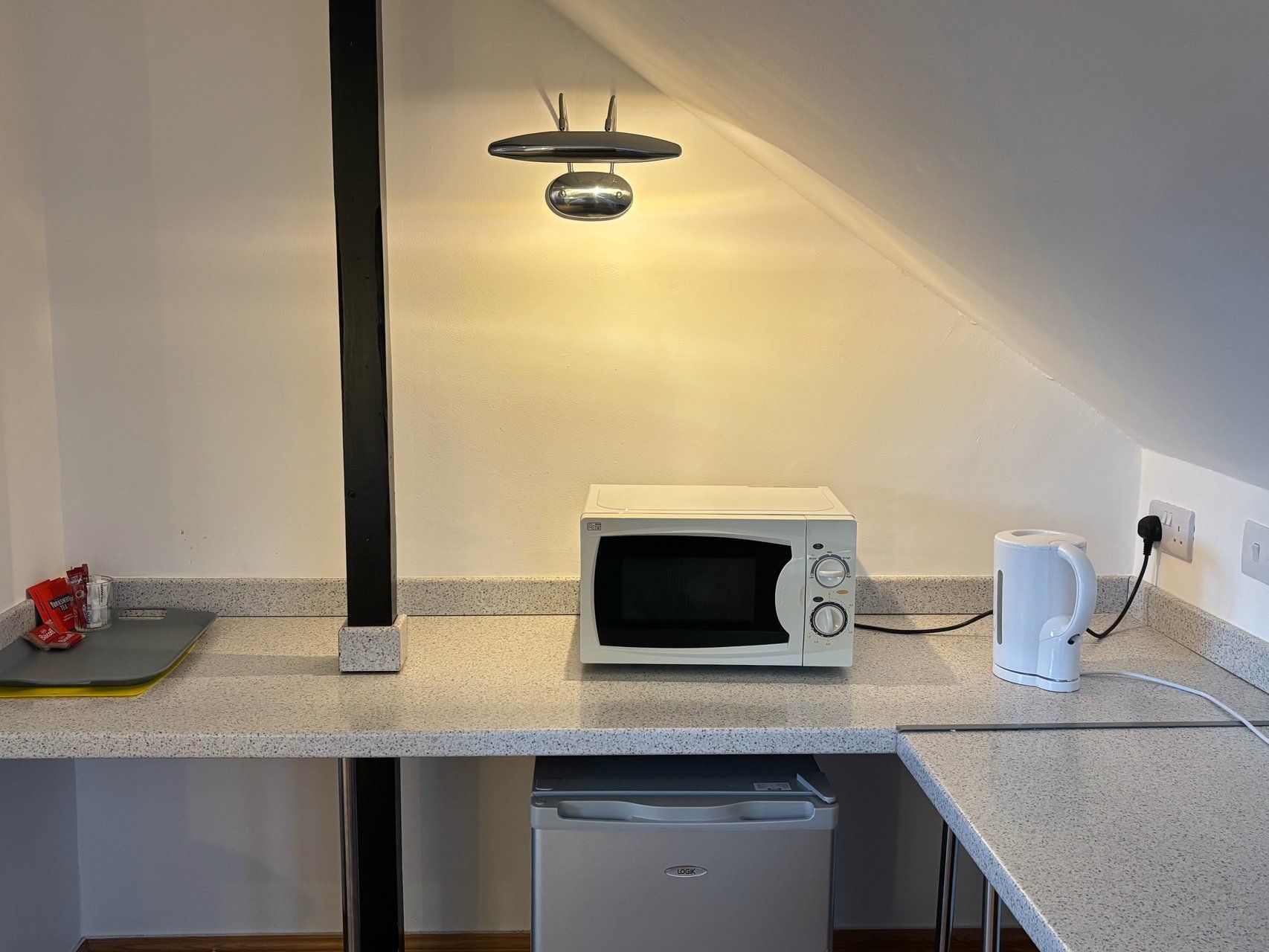 A compact kitchenette with a microwave, a coffee maker, and a dishwasher.