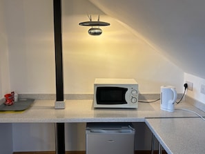 A compact kitchenette with a microwave, a coffee maker, and a dishwasher. - GuestReady – Restful Double En-Suite in Gloucester (Gloucester)