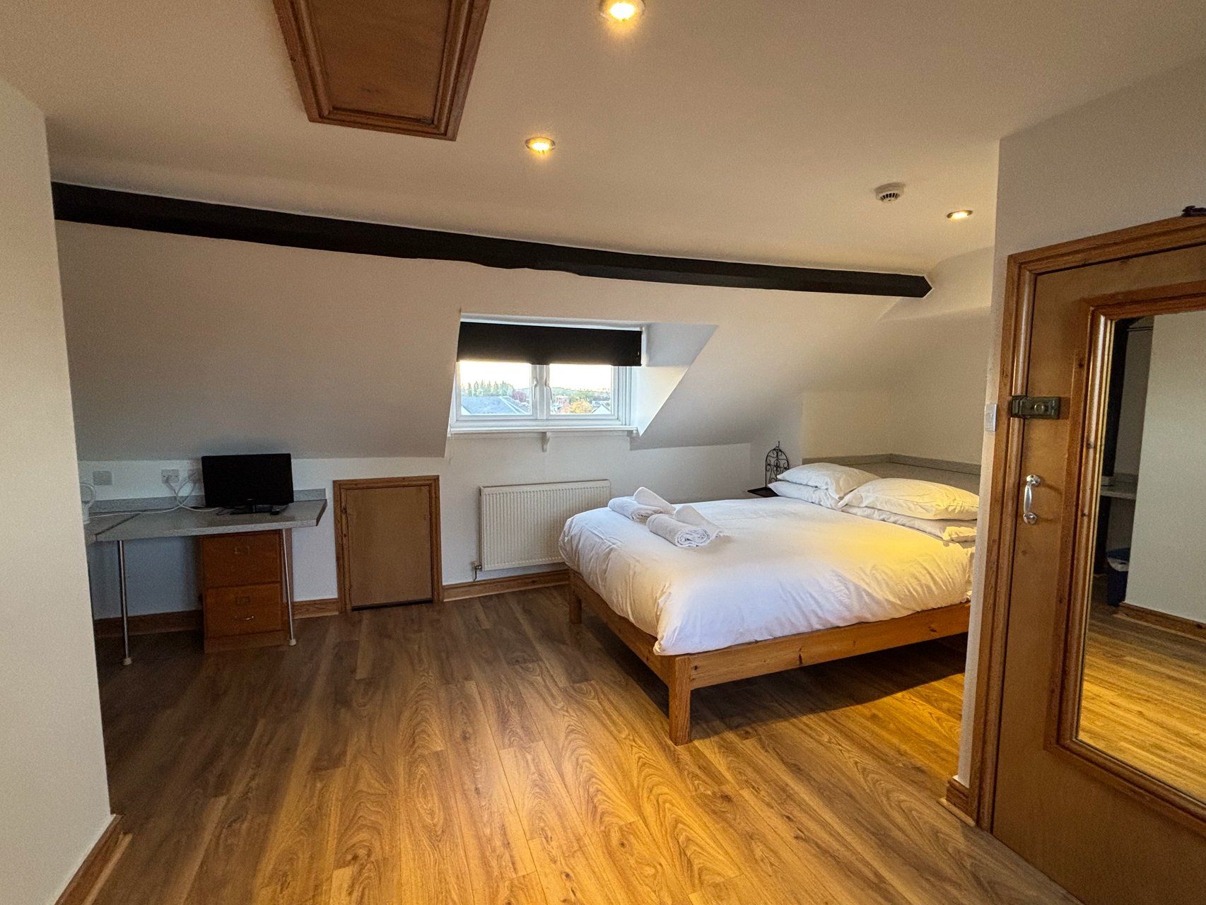 A bedroom with a bed, a desk, and a window.
