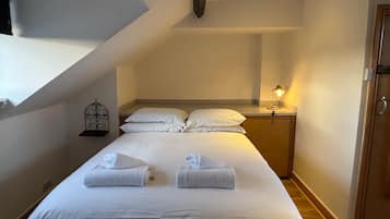 A hotel room with a bed, a nightstand, a lamp, and a decorative wall piece.