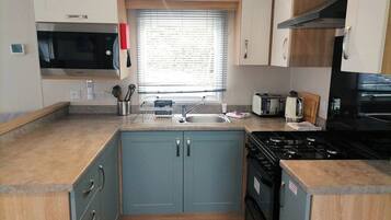 A compact kitchen with a microwave, stove, sink, and cabinets.
