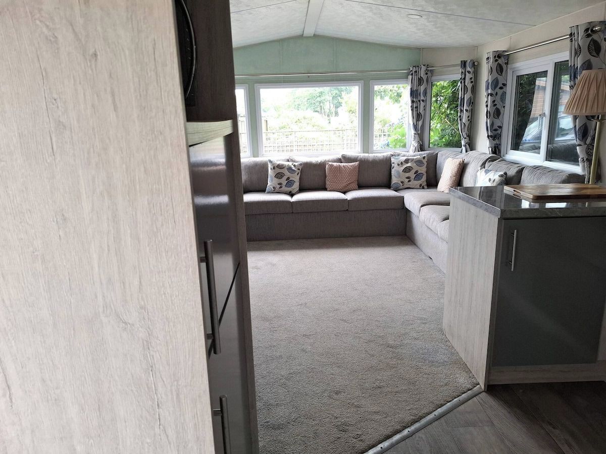 A cozy interior with a sofa set, a kitchen area, and a view through a window.