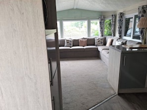 A cozy interior with a sofa set, a kitchen area, and a view through a window.