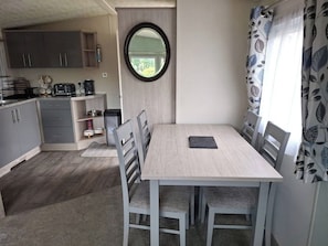 A compact kitchen with grey cabinets, a round mirror, and a dining table with chairs.