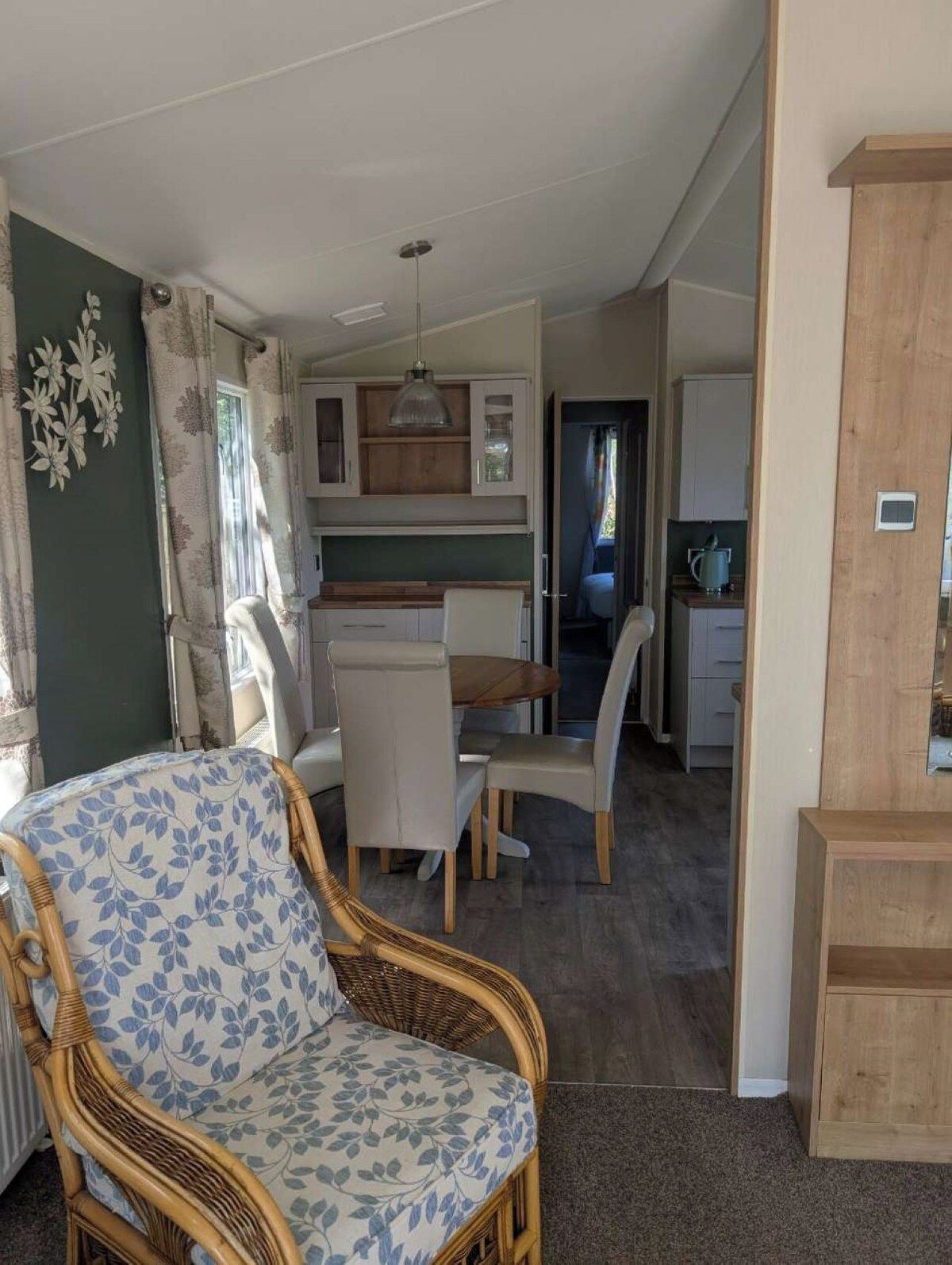 Un espacio habitable compacto con comedor, kitchenette y una silla de mimbre.