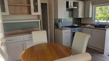 Una cocina compacta con una isla central, muebles blancos y un ventanal que proporciona luz natural.