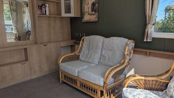 Una habitación acogedora con un sofá de mimbre, un aparador de madera y un cuadro en la pared.