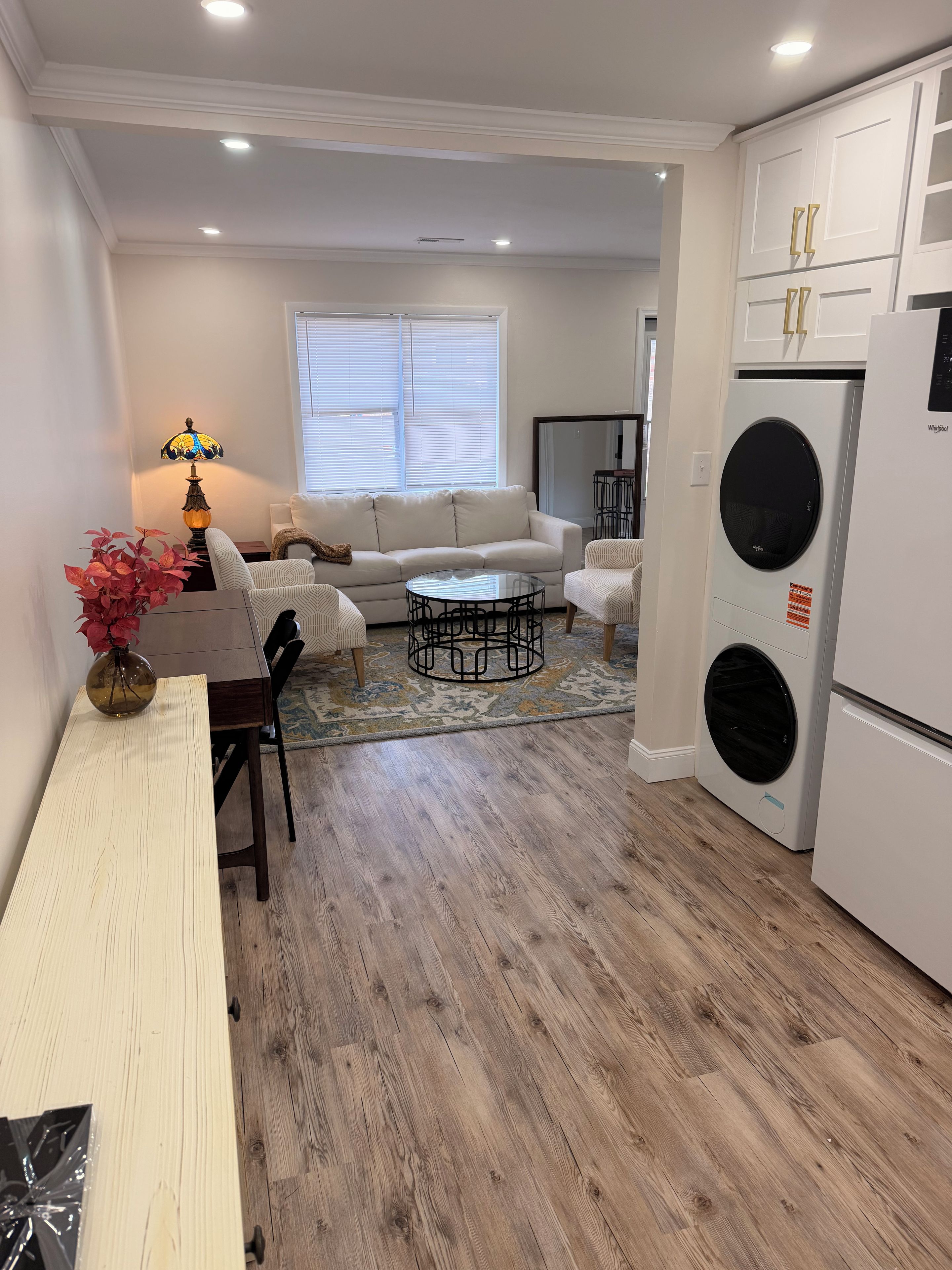 A compact living space with a sofa, coffee table, dining table, and a washing machine.