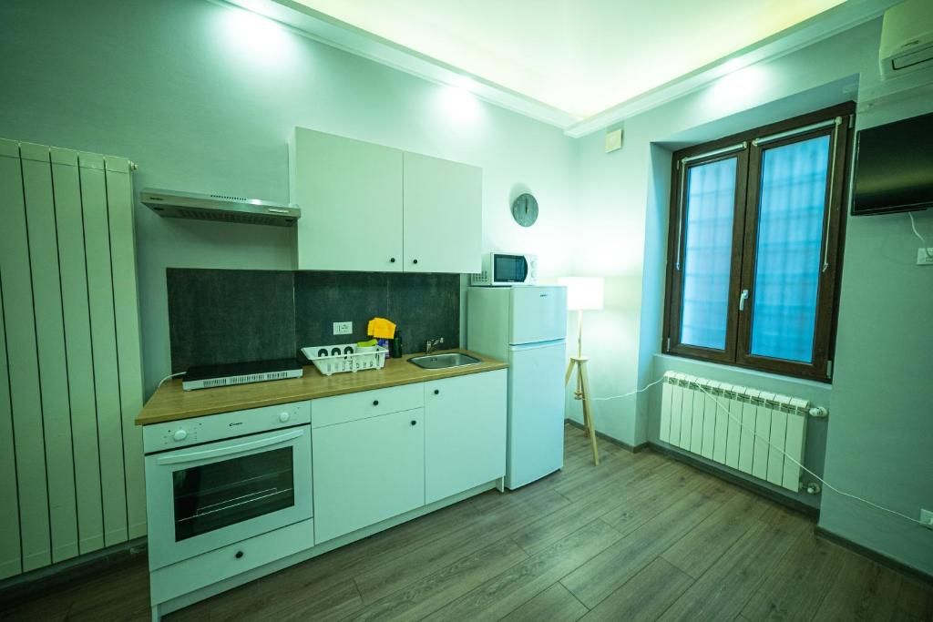 Une cuisine compacte avec des meubles blancs, un four à micro-ondes, un petit réfrigérateur et un plan de travail en bois.