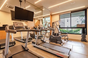 Een fitnessruimte met loopbanden, elliptische trainers en gewichten.