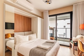 Habitació d'hotel amb llit, escriptori, cadira, televisió i un balcó amb taula i cadires.