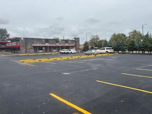 A parking lot with marked spaces and a building with a brick facade in the background.