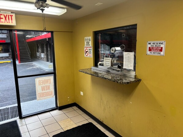 A reception area with a glass door, a small counter, and various signs including 'EXIT' and 'WE RESERVE THE RIGHT TO REFUSE SERVICE TO ANYONE'.