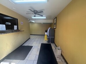 A hallway with a ceiling fan, a reception desk, a trash bin, and a caution sign on the floor.