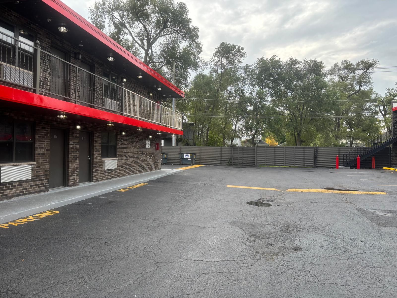 Un bâtiment doté d’un auvent rouge, d’une façade en briques et d’un parking avec des places délimitées.