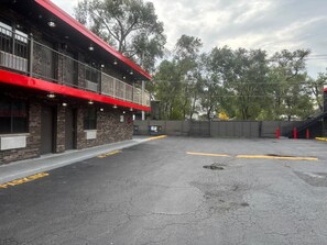 A building with a red awning, a brick facade, and a parking lot with marked spaces.